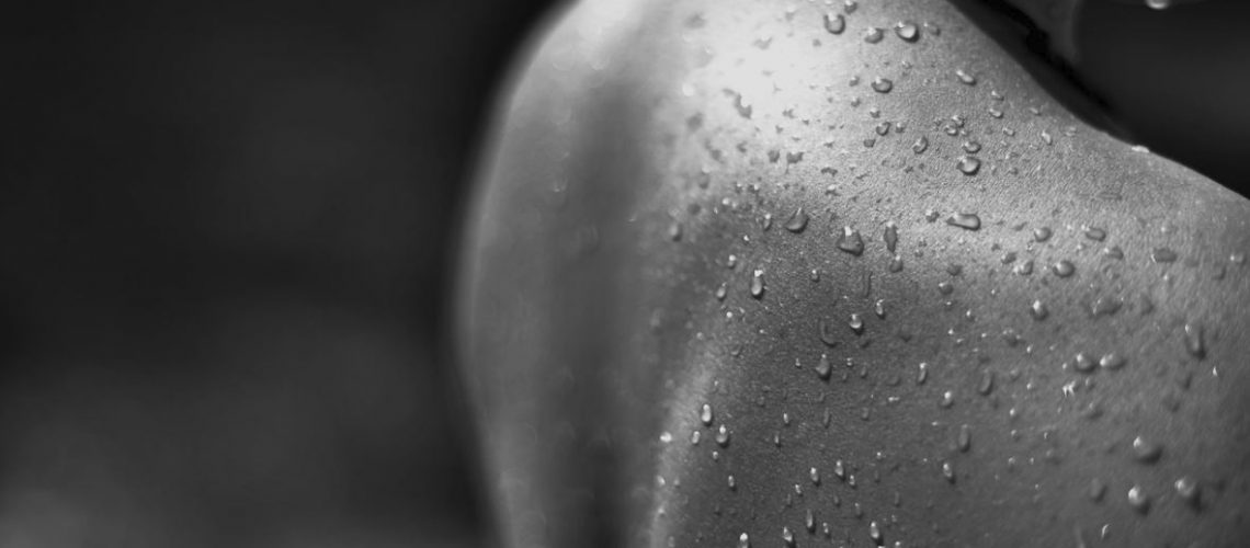A black and white image of a persons back covered in water droplets